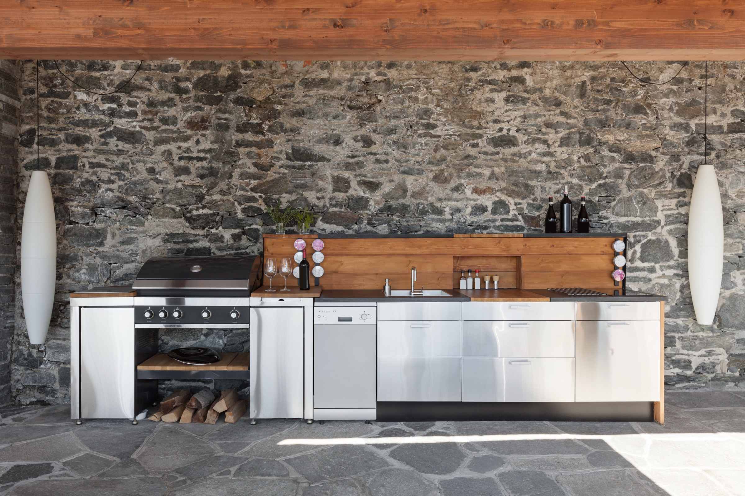 Luxury outdoor kitchen set against a natural stacked-stone wall built by Lastovica Masonry in Omaha, NE