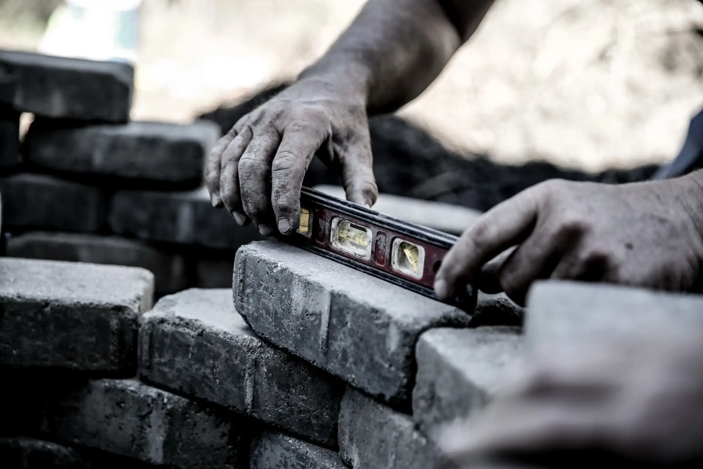 Mason using a level to set a natural stone block wall — Lastovica Masonry in Omaha, NE